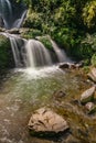 Vertical shot of the waterfall cascading over rocks in sunlight in Rock Garden, Darjeeling, India