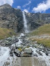 Vertical shot of a waterfall flowing from a huge rocky hill in the Alps in Frabce