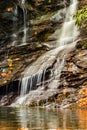 Vertical shot of the waterfall water pouring in a lake in the forest on a sunny day Royalty Free Stock Photo
