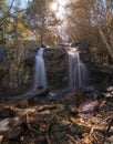 Vertical shot of waterfalls through rocks with long exposure in the forest on a sunny day Royalty Free Stock Photo