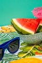 Vertical shot of watermelon wedges in a bowl, blue sunglasses on a colorful tablecloth