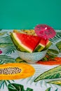 Vertical shot of watermelon wedges in a bowl on a colorful tablecloth,decorated with a tiny umbrella