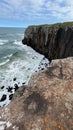 Vertical shot of a wavy sea washing underside of high cliffs in Morro Da Guarita, Brazil