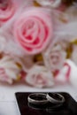 Vertical shot of wedding rings in front of a flower bouquet Royalty Free Stock Photo