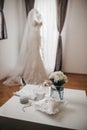 Vertical shot of the wedding rings on a white table with the bride's dress in the background Royalty Free Stock Photo