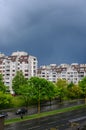 Vertical shot of white apartment buildings surrounded by beautiful green trees under a rainy sky Royalty Free Stock Photo