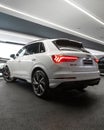 Vertical shot of a white Audi RSQ3 car from the back in a cool modern showroom