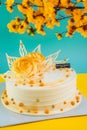 Vertical shot of a white birthday cake with a yellow rose on it and orange flowers background