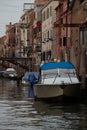 Vertical shot of a white boat in a canal surrounded by low-rise old buildings of Venice, Italy Royalty Free Stock Photo