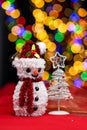 Vertical shot of the white Christmas tree and snowman figurine on a blurred lights background Royalty Free Stock Photo