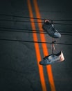 Vertical shot of the white dirty sneakers hanging from the street wire on an asphalt road background Royalty Free Stock Photo