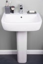 Vertical shot of a white modern pedestal bathroom sink with soap and toothbrushes Royalty Free Stock Photo