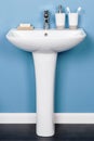 Vertical shot of a white modern pedestal bathroom sink with soap and toothbrushes Royalty Free Stock Photo