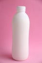 Vertical shot of a white plastic bottle isolated on a pink background Royalty Free Stock Photo