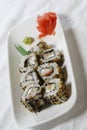 Vertical shot of a white plate of tasty sushi rolls with black and white sesame seeds