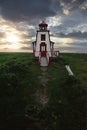 Vertical shot of white and red building in green field under cloudy sunset sky Royalty Free Stock Photo