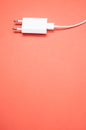Vertical shot of a white smartphone charger on a peach-colored surface