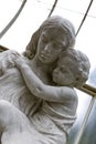 Vertical shot of a white statue of a mother holding her son in a museum