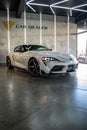 Vertical shot of a white Toyota Supra A90 MK5 front view with the right headlight on