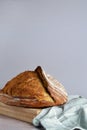 Vertical shot of whole sourdough bread crust with ridge on cloth napkin in turquoise tones