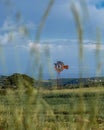 Vertical shot of a windmill with a blurred grass and blue cloudy sky Royalty Free Stock Photo