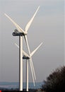 Vertical shot of windmill wings under a grey sky and bushes on the forefront