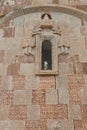 Vertical shot of a window of ancient Armenian church with saints sculptures and letters on the wall