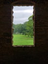 Vertical shot of the window with a view of an alley of trees in the garden