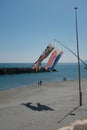 Vertical shot of windsocks hanging from a pole with people standing near the sea in background Royalty Free Stock Photo