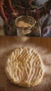 Vertical shot of a woman baking bread and dropping flour on the dough