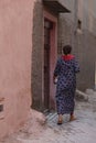 Vertical shot of a woman dressed in Arabic clothes walking on a street in Medina