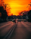 Vertical shot of a woman passing a street in Bucharest against a golden sunset sky