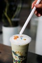 Vertical shot of a woman's hand preparing to put a straw in a delicious cup of bubble tea Royalty Free Stock Photo
