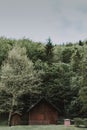 Vertical shot of a wooden barn surrounded by trees under a cloudy sky at daytime Royalty Free Stock Photo