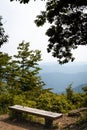 Vertical shot of a wooden bench with the view of mountains on a sunny day Royalty Free Stock Photo