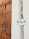 Vertical shot of a wooden door with an arabic sign on the wall