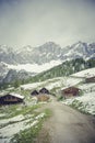 Vertical shot of wooden houses on the mountains covered in snow in wintertime under the crazy sky Royalty Free Stock Photo