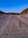 Vertical shot of the wooden stairs at the beach surrounded by small green hills at sunset Royalty Free Stock Photo