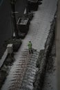 Vertical shot of a worker cleaning the snow off the paved sidewalk with a shovel