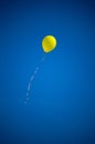 Vertical shot of a yellow balloon in the air with a blue sky in the background Royalty Free Stock Photo