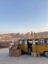 Vertical shot of a yellow cafe bus parked at tourist attraction of rocky hills in Goreme