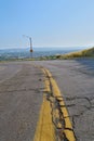 Vertical shot of yellow centerline on cracked asphalt road under blue sky Royalty Free Stock Photo