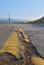 Vertical shot of yellow centerline on cracked asphalt road under blue sky Royalty Free Stock Photo