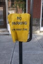 Vertical shot of a yellow, dented NO PARKING TOW AWAY ZONE sign at a street Royalty Free Stock Photo