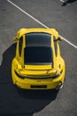 Vertical shot of a yellow Porsche parked outdoors