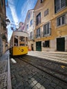 Vertical shot of a yellow tram in a narrow street in Lisbon, Portugal