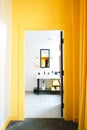 Vertical shot of the yellow wall with a bathroom visible through a doorway