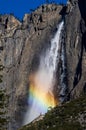 Vertical shot of the Yosemite Falls flowing with sunlight catching a rainbow