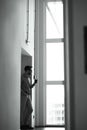 Vertical shot of a young businessman drinking fresh coffee while standing in the office and looking out the window Royalty Free Stock Photo