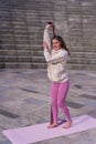 Vertical shot of a young caucasian woman doing an overhead tricep exercise using a resistance band